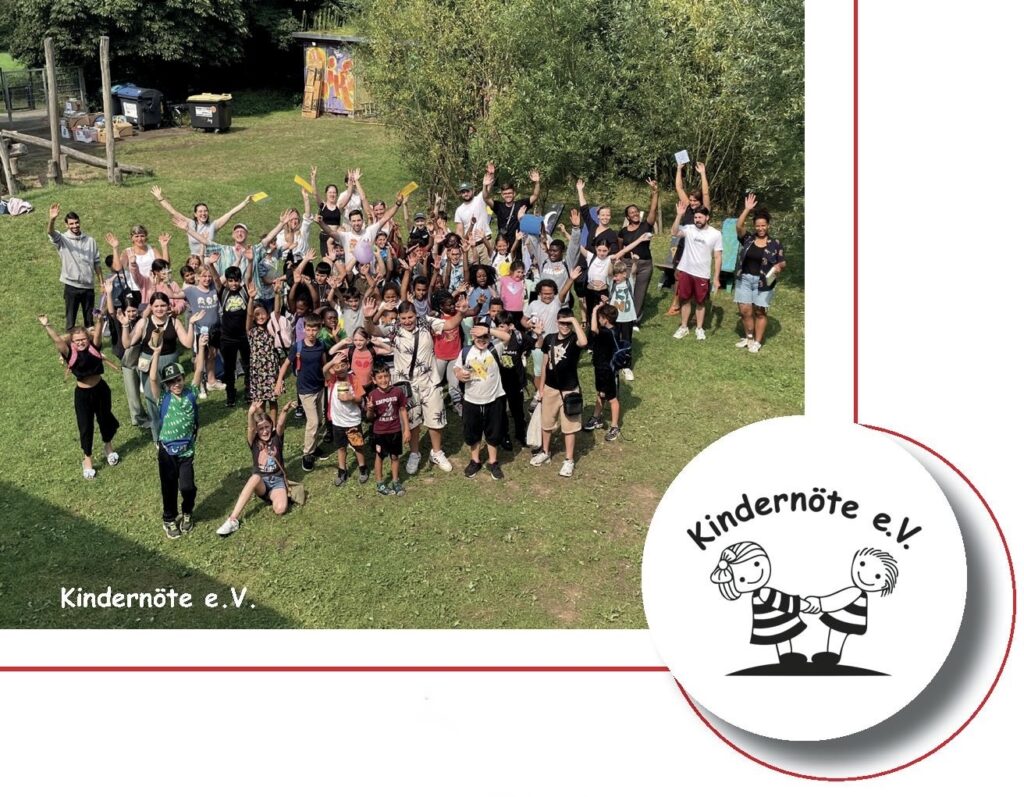 Gruppenfoto: viele Kinder und Betreuer jubeln mit erhobenen Armen auf einer Wiese, daneben das Vereinslogo